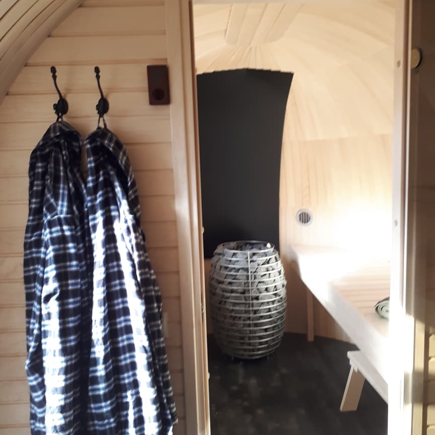Blick in die Iglusauna mit Saunaofen und Bademänteln